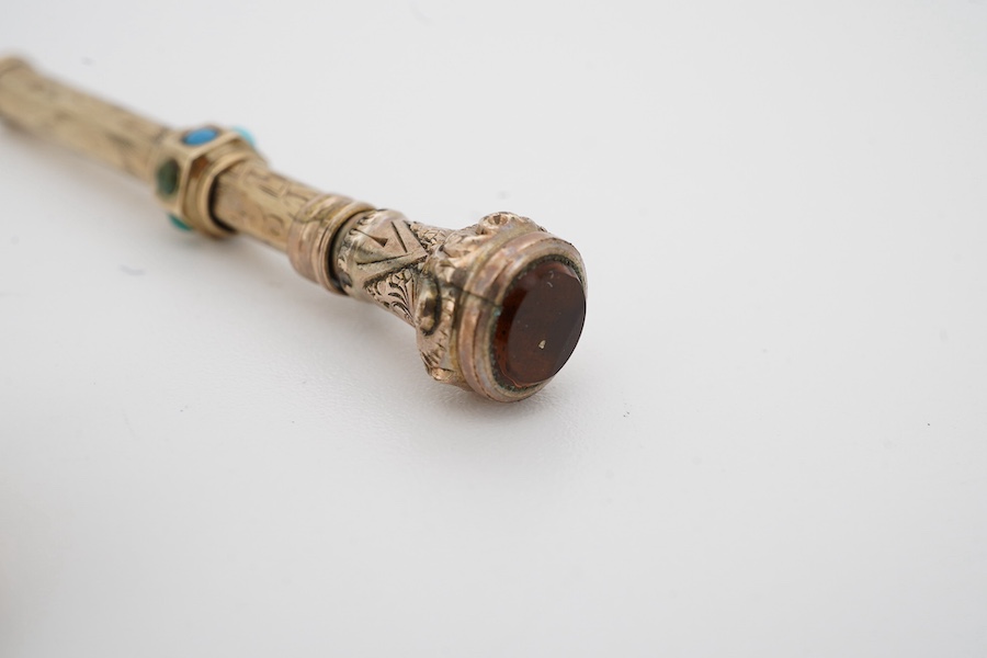 An early 20th century engraved yellow metal, citrine and turquoise set propelling pencil (turquoise stone missing), 42mm, together with a yellow metal whistle charm. Condition poor to fair